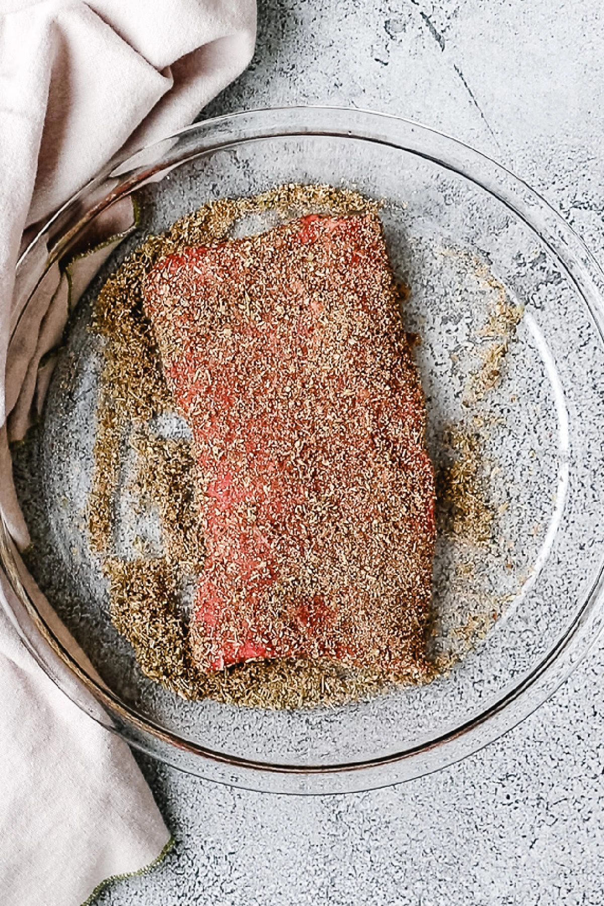 Top down view of flat iron steak in a dish with seasoning.