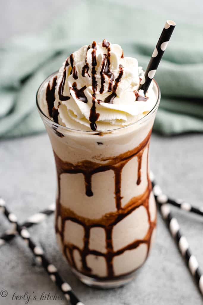 Tall cocktail glass with a frozen mudslide and whipped cream.
