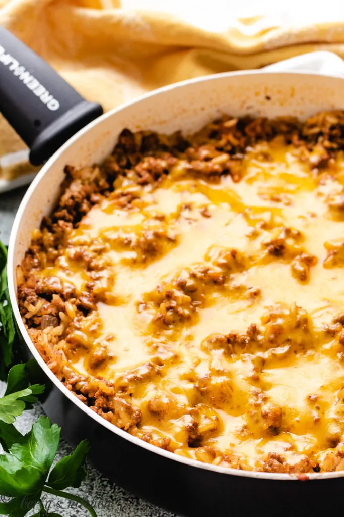 Cheesy rice and ground beef in a black pan.