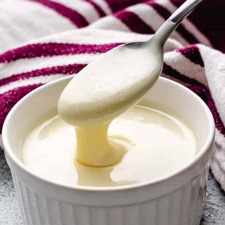 Spoon stirring homemade sweetened condensed milk.