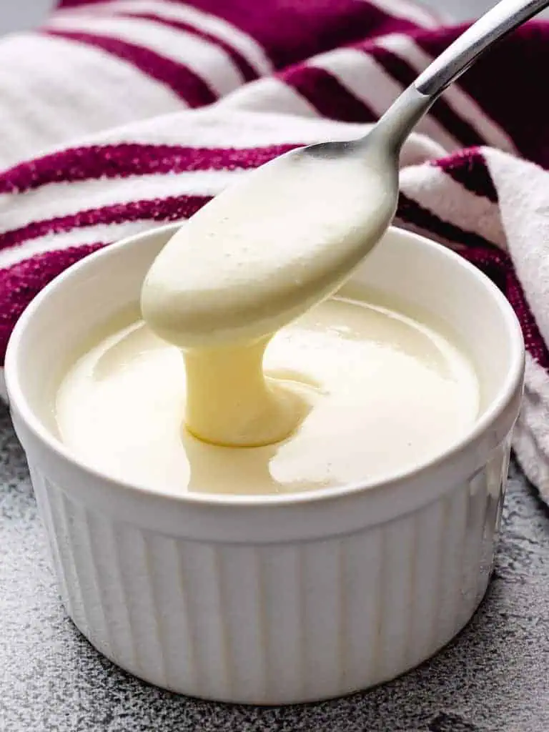 Close up view of sweetened condensed milk in a white bowl.