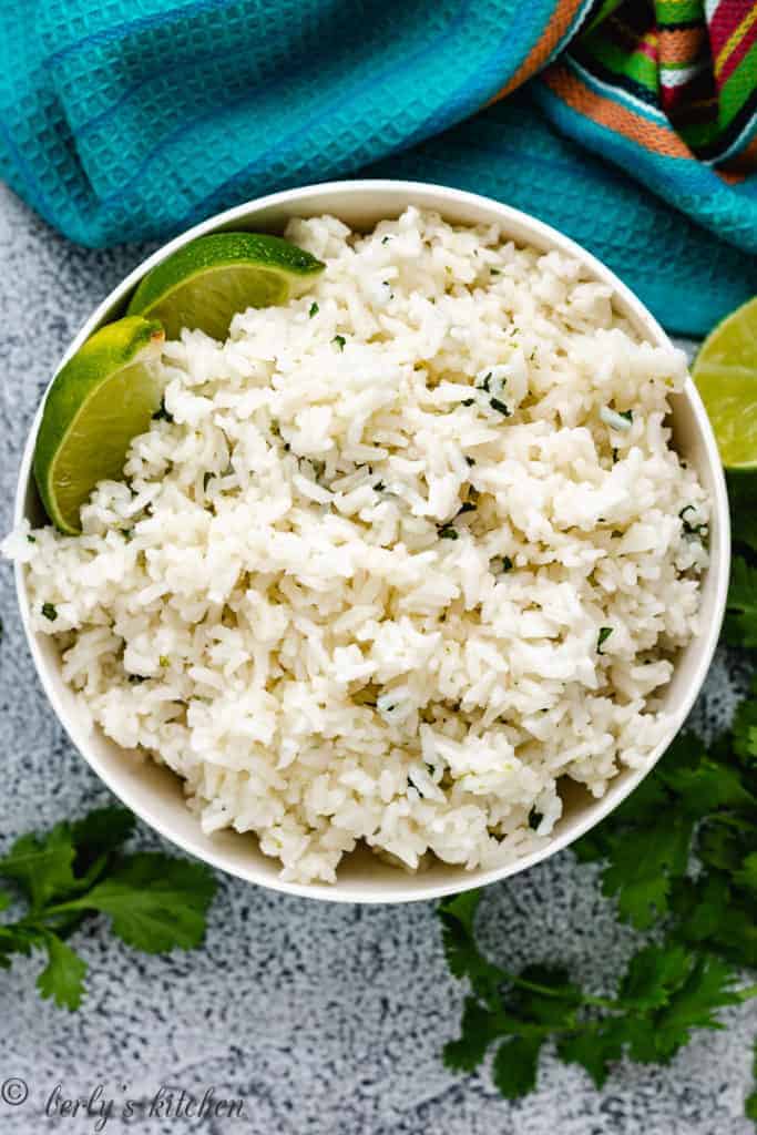 Top down view of fluffy rice with cilantro and lime.