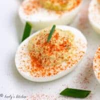 Paprika sprinkled over filled deviled egg.