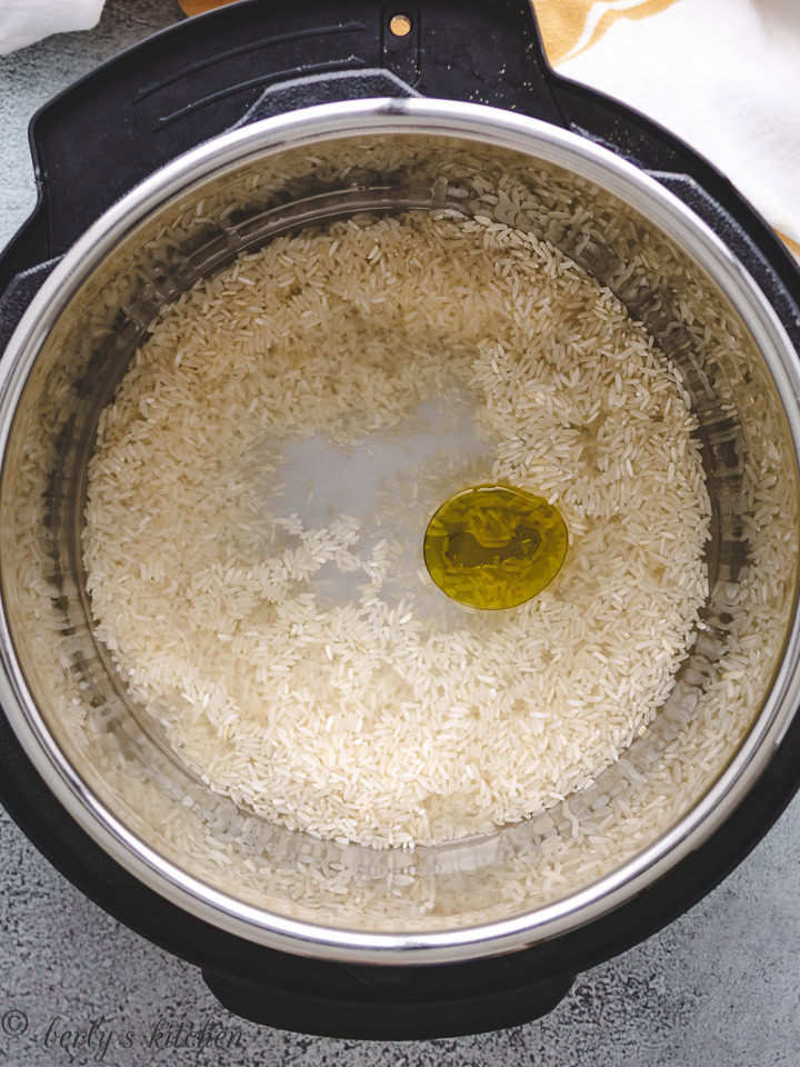 Top down view of rice, water, and oil in an Instant Pot.