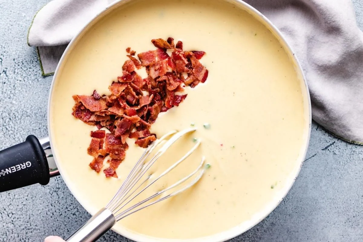 Cheese sauce in a pan with crumbled bacon.