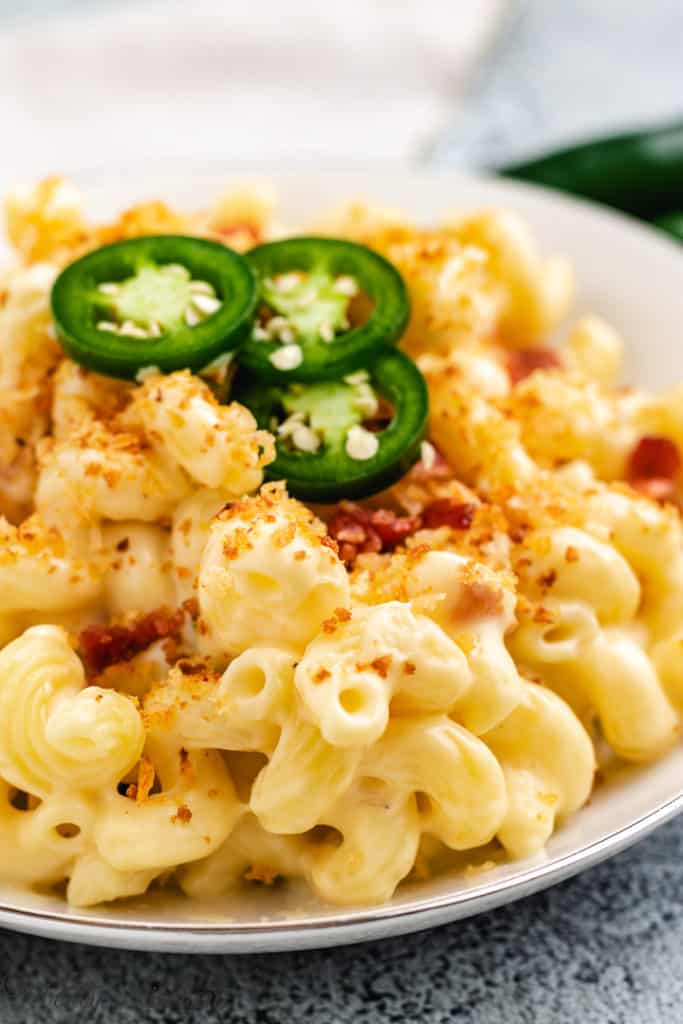 Close up view of macaroni and cheese with sliced jalapenos.