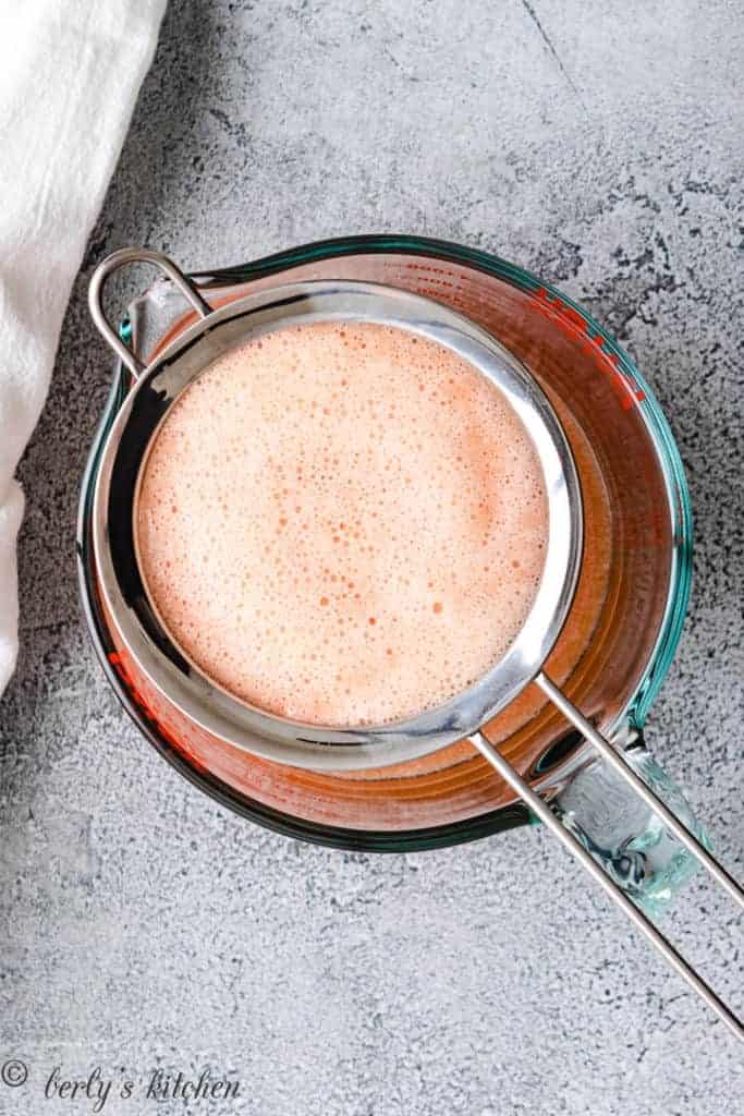 Fruit juice poured into a strainer.