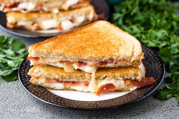 The bacon grilled cheese sandwich halved to show melting cheese.