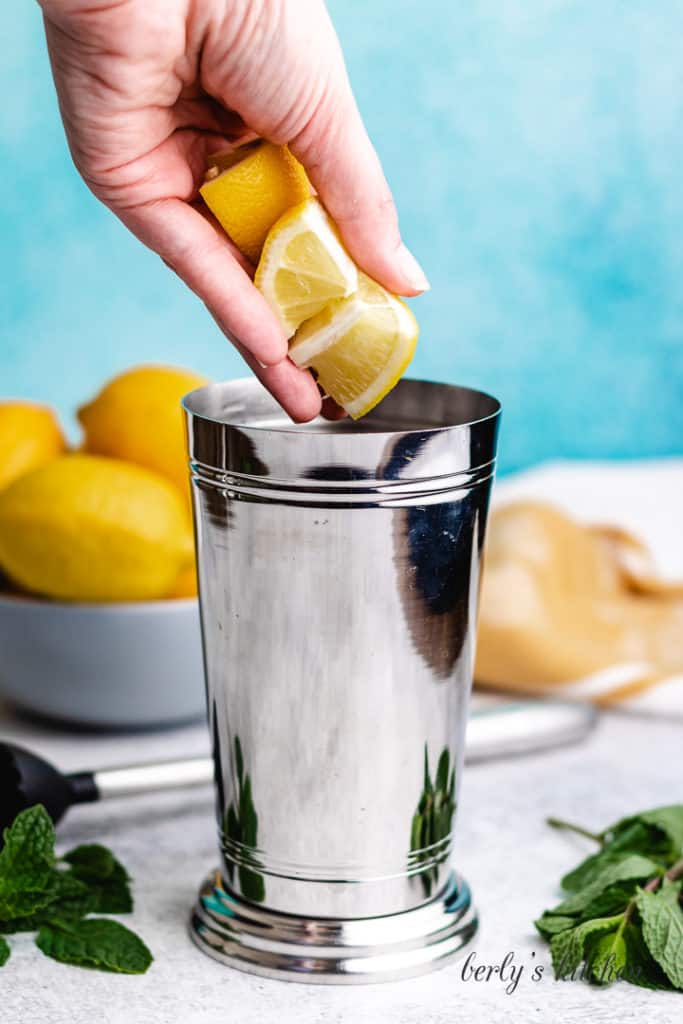 Lemon wedges being placed in a shaker.