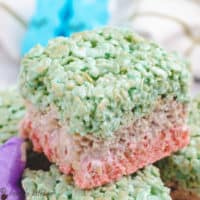 Layered easter rice krispie treats stacked on a white plate.