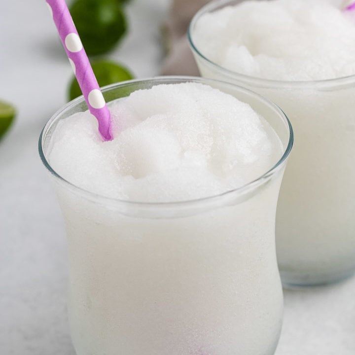 Easy Frozen Daiquiri White frozen drink in a glass with a pink straw.