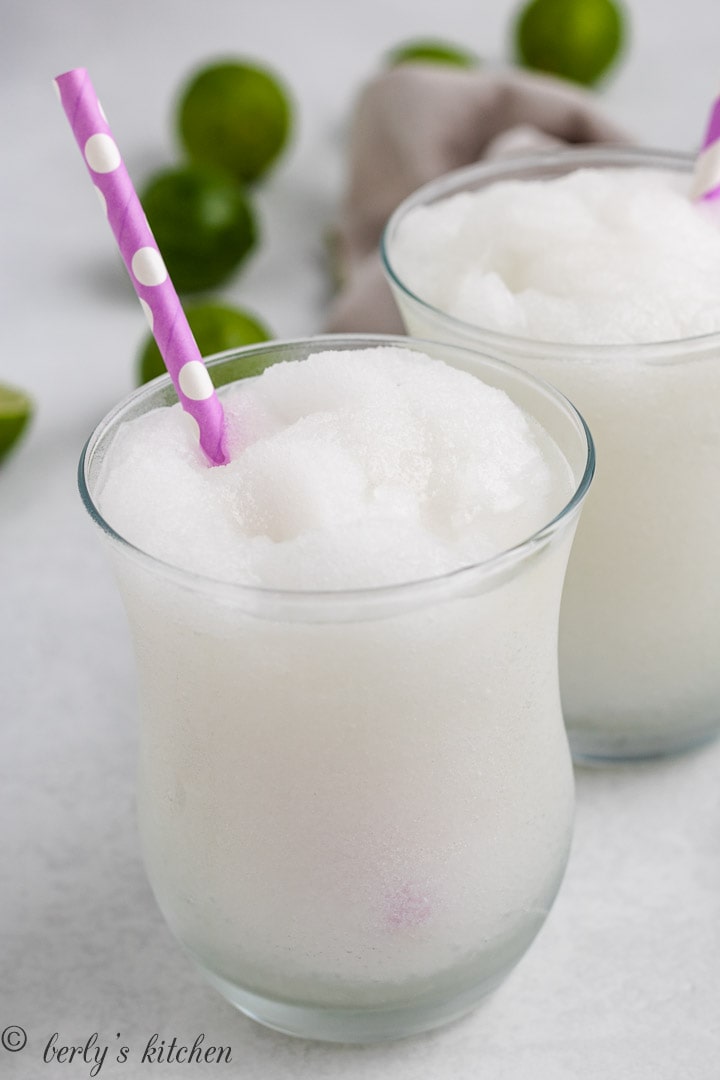 White frozen drink in a glass with a pink straw.