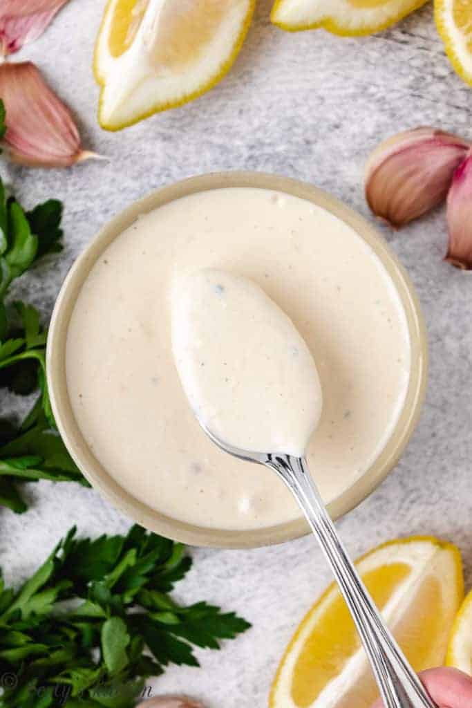 Top down view of caesar salad dressing on a spoon.