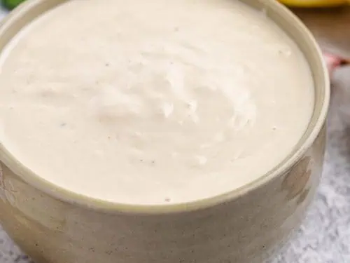 Close up of salad dressing in a tan dish.