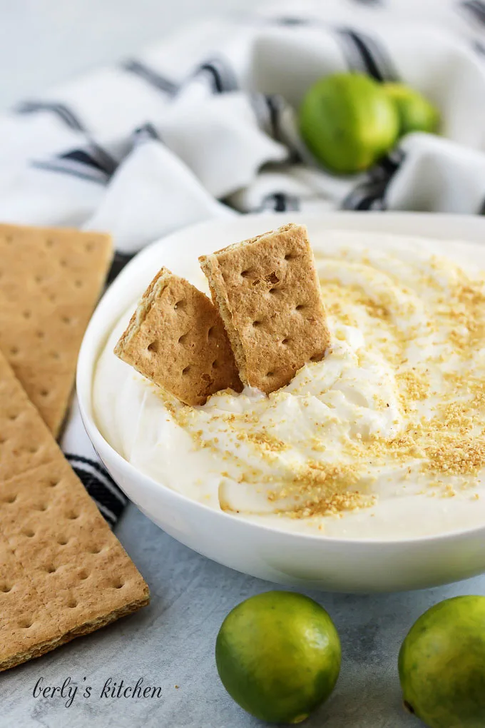 Key lime cheesecake dip, in a bowl, topped with graham cracker crumbs.