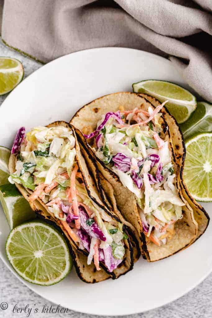 Top down view of mahi mahi tacos on a plate with limes.