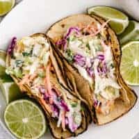 Top down view of mahi mahi tacos on a white plate.