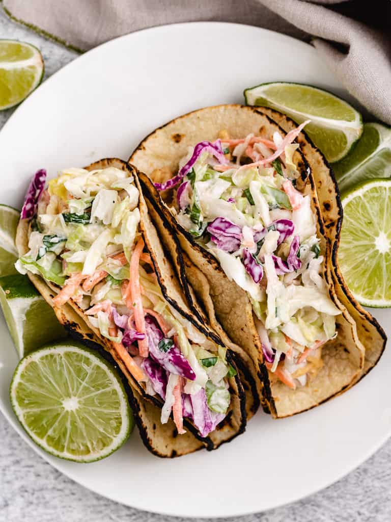 Top down view of mahi mahi tacos on a white plate.
