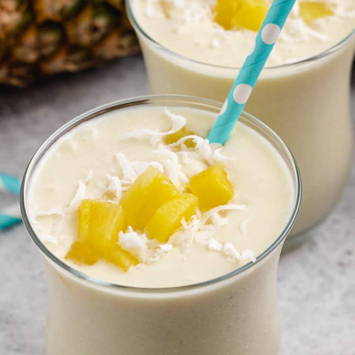 Pina colada smoothie topped with fresh pineapple and coconut.