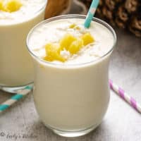 Two glasses of smoothie with pineapple and shredded coconut.