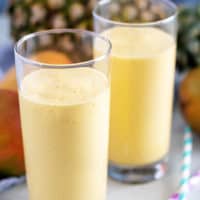 Tall glasses filled with pineapple mango smoothie.