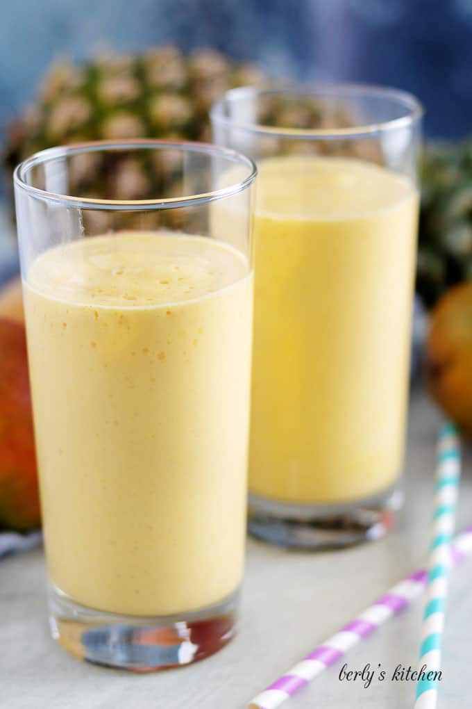 Two tall glasses filled with pineapple smoothie.