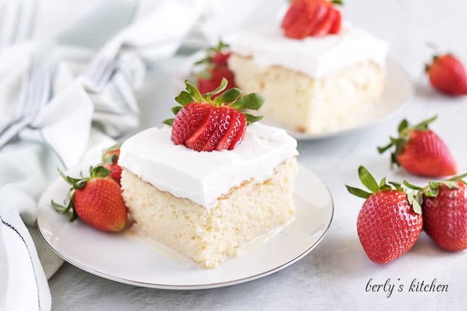 A piece of tres leches cake garnished with a sliced strawberry.