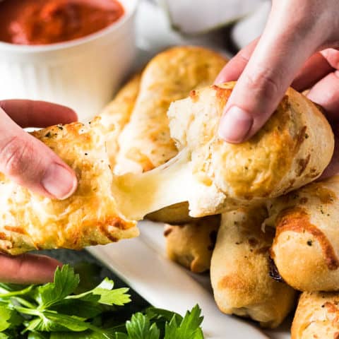 A breadstick being broken apart to show gooey melted cheese