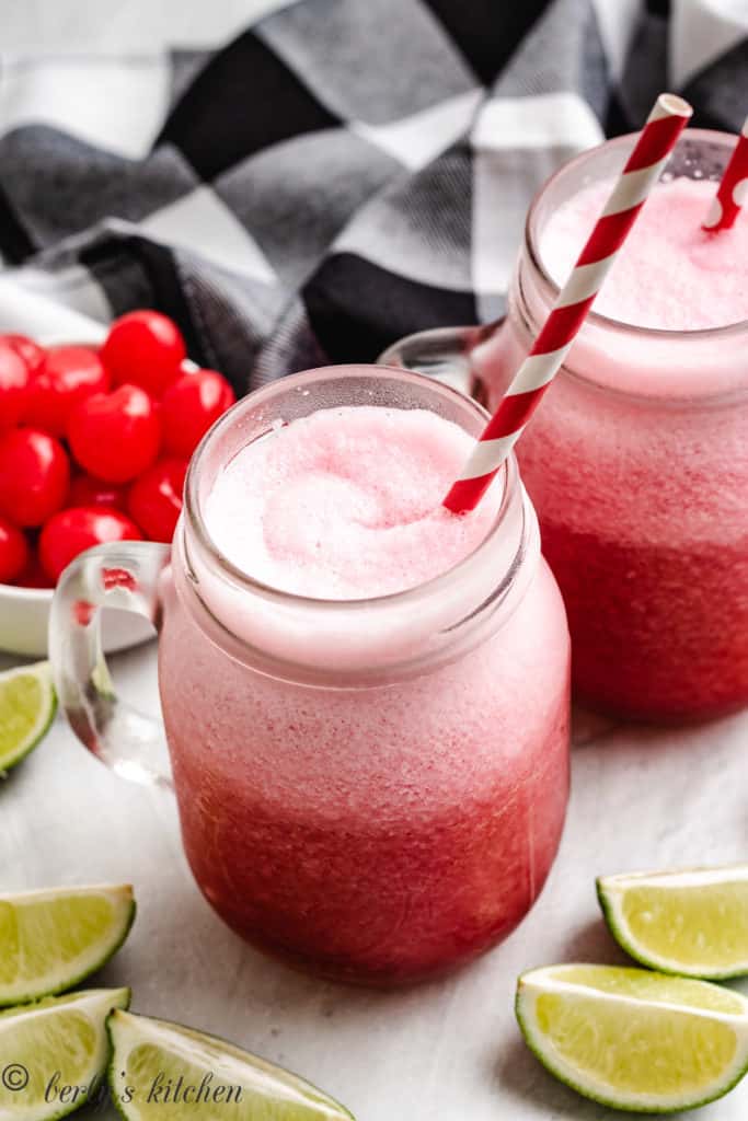 Two glasses of cherry limeade slush with straws.