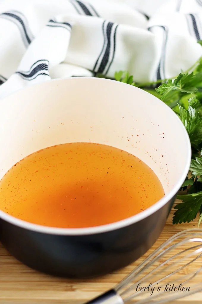 Spices and chicken broth in a pan.
