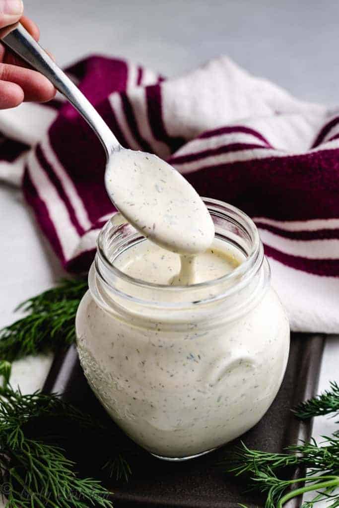 Dill dressing being stirred with a spoon.