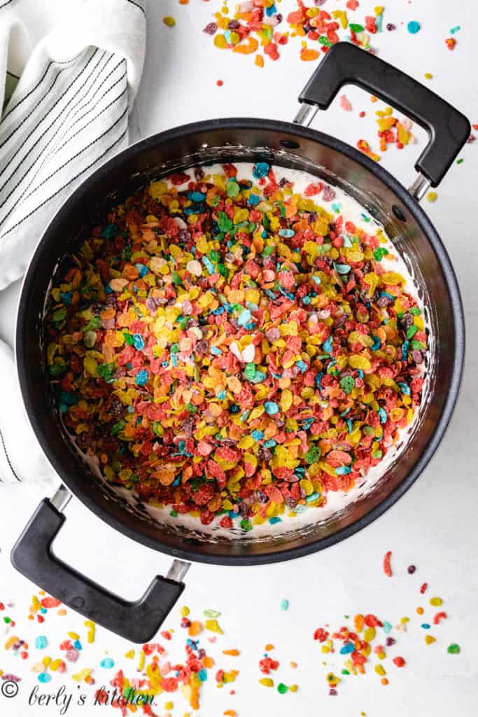 Fruity Pebbles on top of melted marshmallows in a pan.
