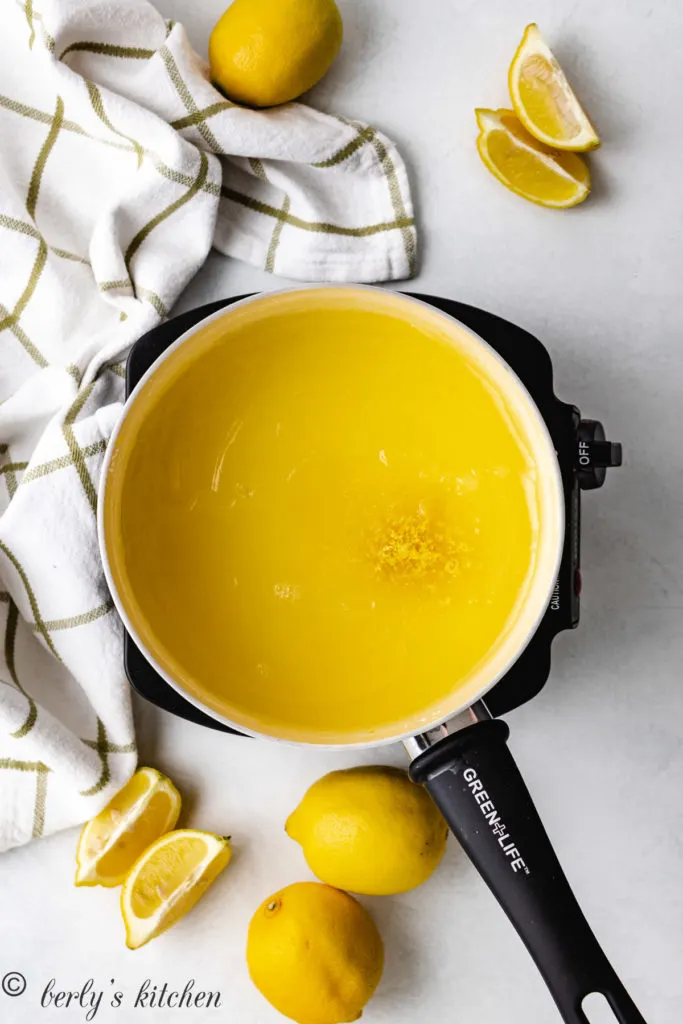 Top down view of lemon pastry filling, lemon zest and lemon juice in a pan.