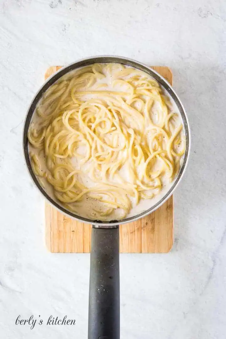Top down view of simple bechamel sauce with noodles in a pan.