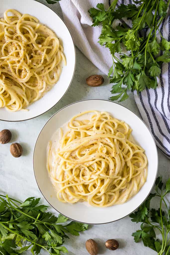 Top down view of noodles in white sauce sprinkled with nutmeg.