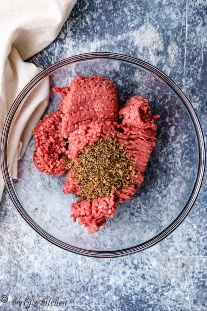 Top down view of ground beef and seasoning in a bowl.