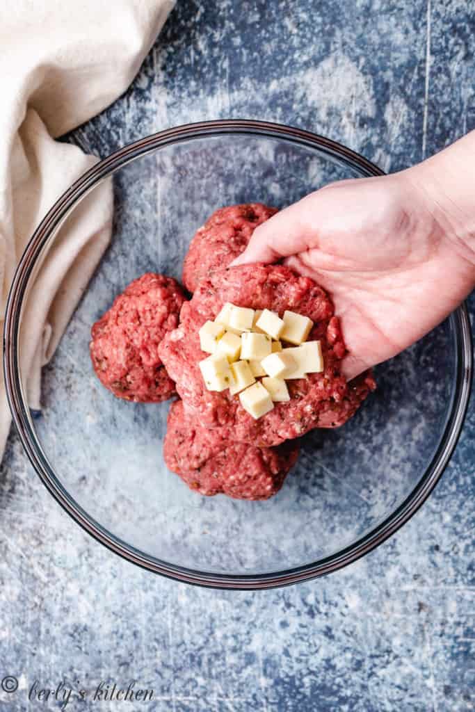 Top down photo of half a burger patty with cheese cubes.