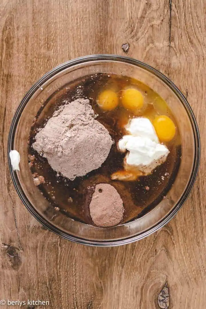 Top down view of ingredients for chocolate cake batter in a bowl.
