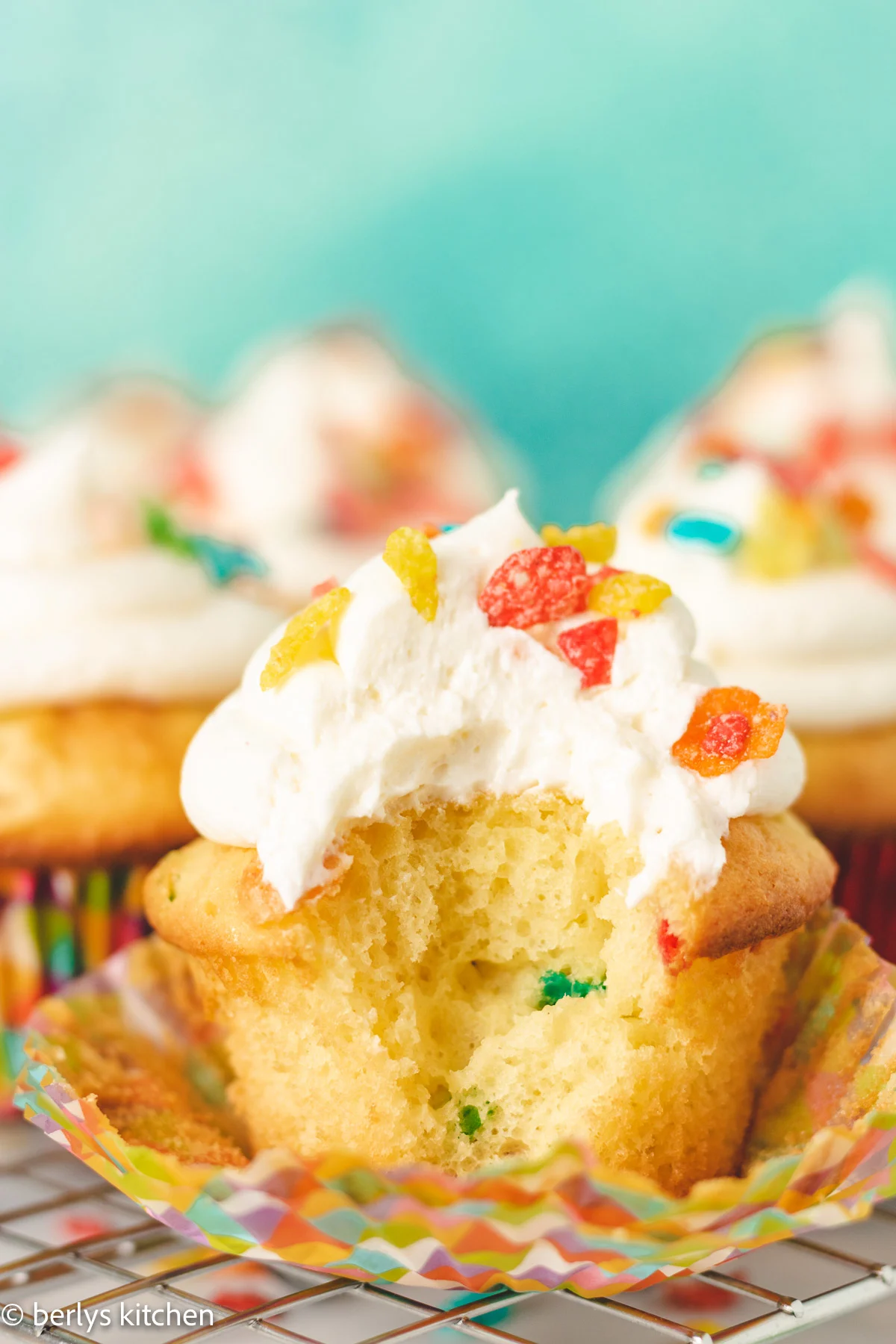 Large bite taken out of a Fruity Pebbles cupcake.