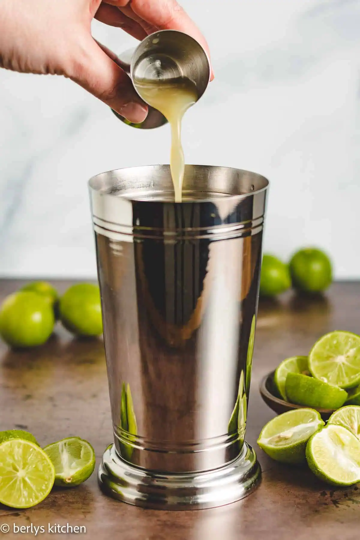 Key lime juice being poured into a shaker.