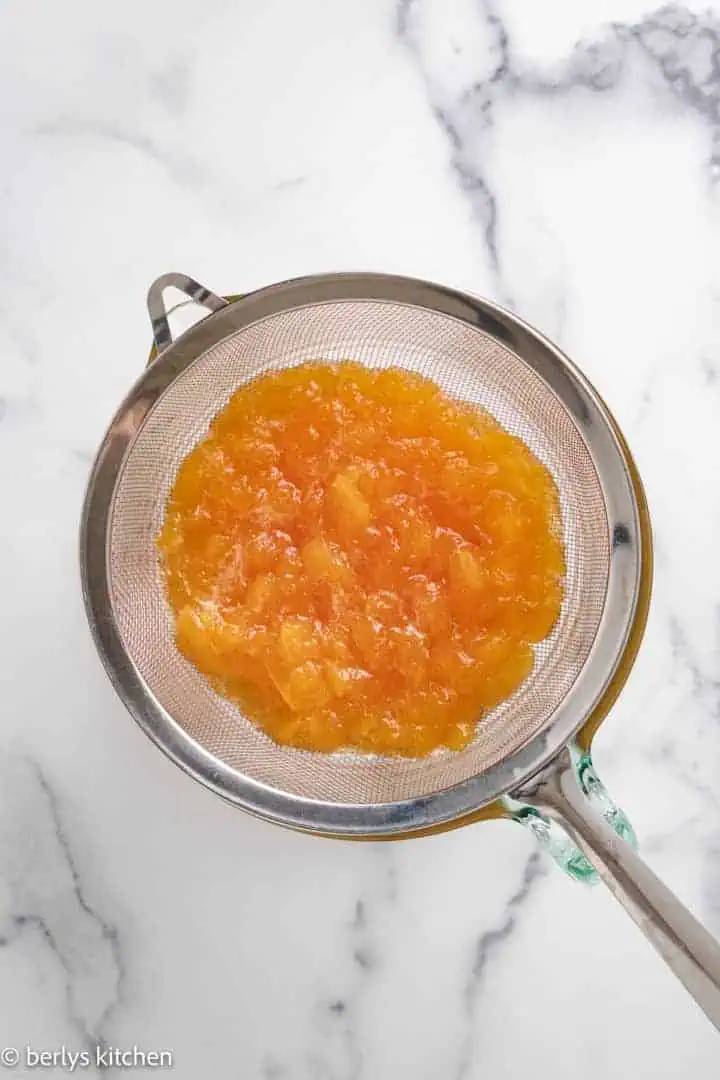 Top down view of peaches in a strainer.