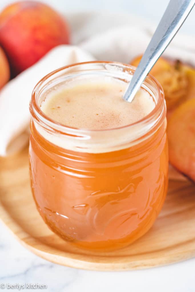 Jar with a spoon and homemade peach syrup.