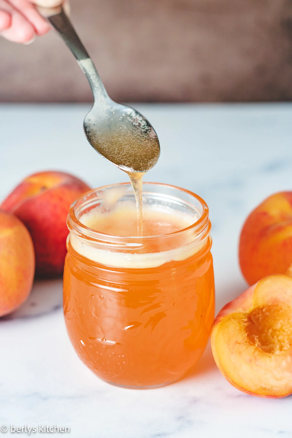 Fresh peach simple syrup on a spoon.