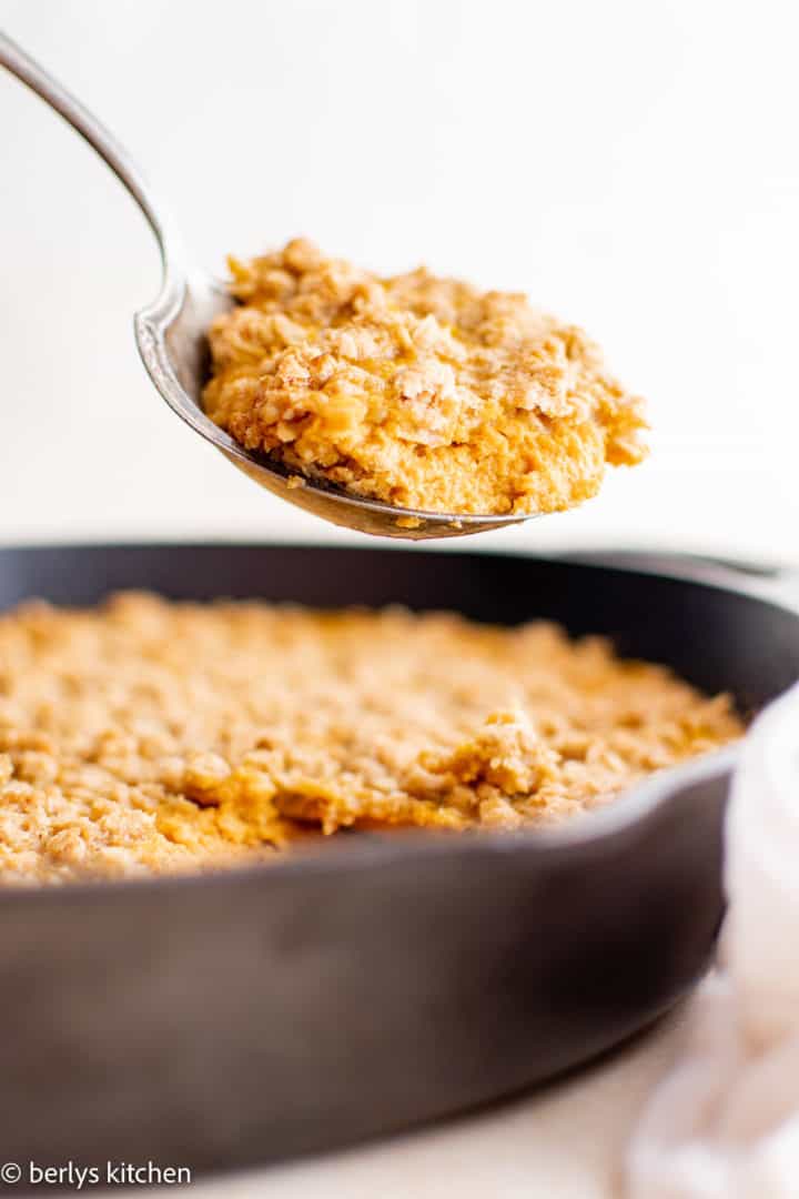 Pumpkin Crisp Spoon scooping pumpkin crisp out of a pan.