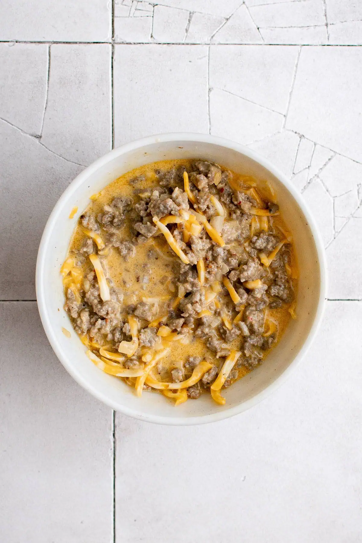 Top down view of mixed ingredients for quiche in a dish.