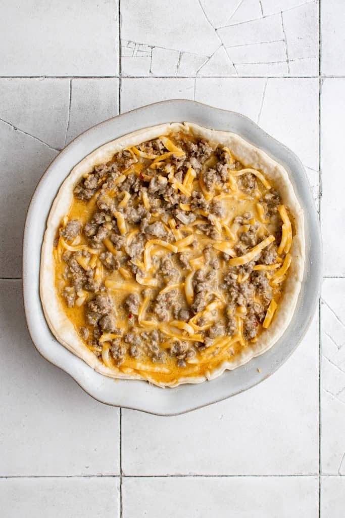 Top down view of unbaked quiche in a baking dish.