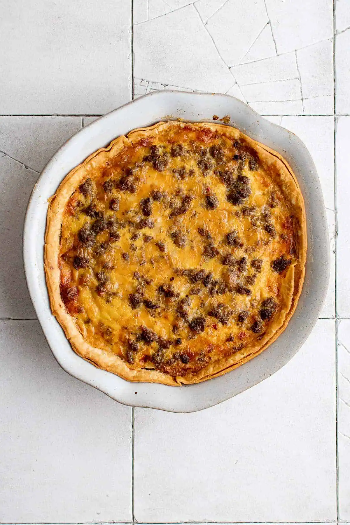 Top down view of sausage quiche in a white baking dish.