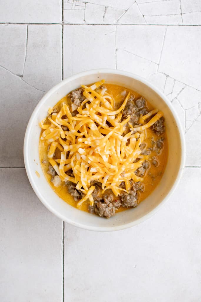 Top down view of egg mixture and cheese in a bowl.