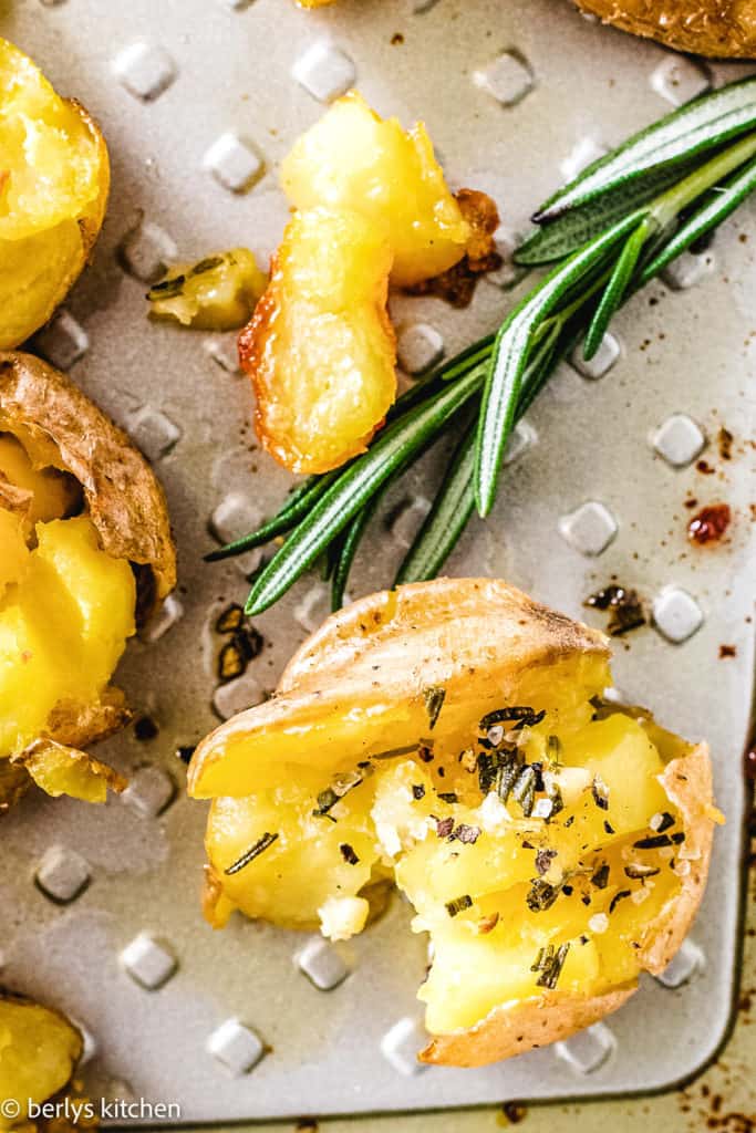 Close up a a baby gold potato with rosemary butter.