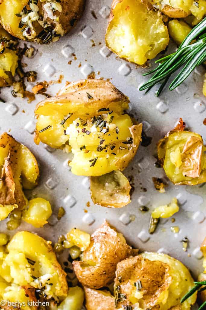 Top down view of smashed potatoes with herb butter.